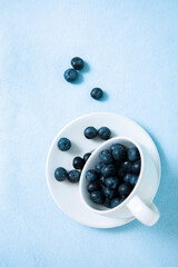 Vertical photo with blueberries sleeping out of a teacup