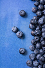 Vertical photo with scattered blueberries in a blue flat plate