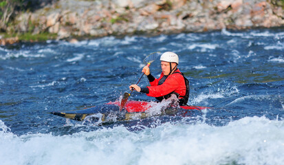 Extreme water sports, rafting on mountain river in kayak. Kayaker man strives for victory, boating championship