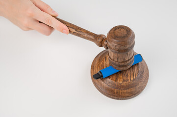 Judge hammering disposable vape with referee's gavel on white table. 
