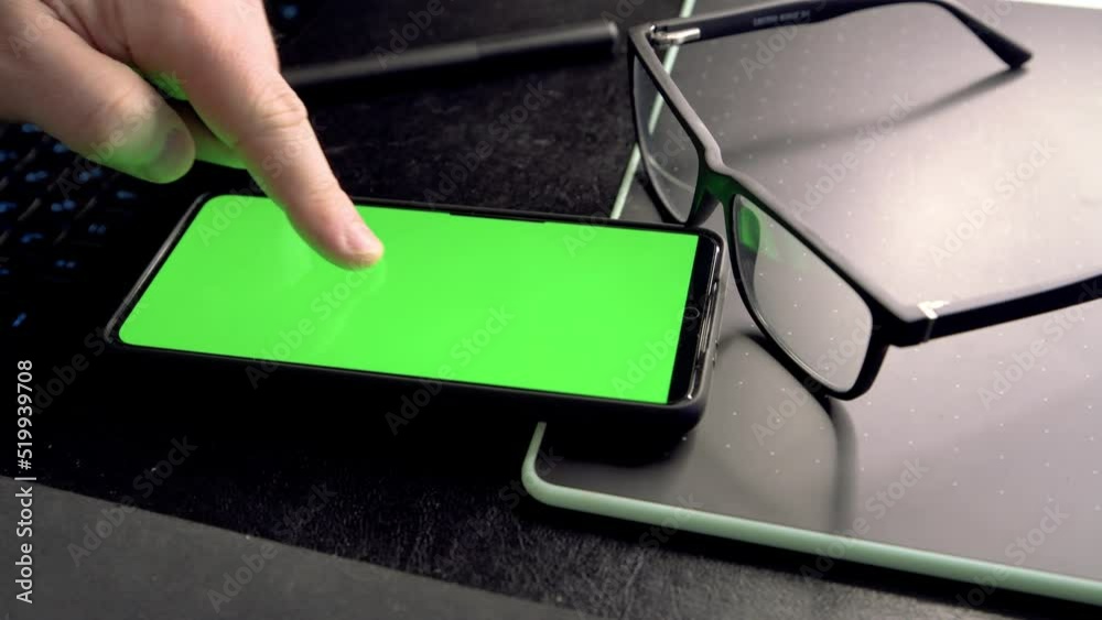 Poster Man unlocking and using mobile phone at his working place. 4k video footage with green screen smartphone