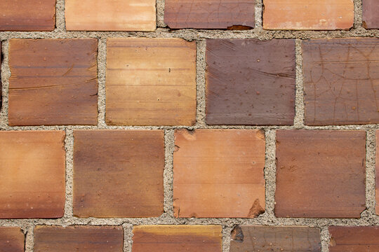 Full frame texture background of an antique multicolor brown clay tile brick wall texture background with exposed mortar and cracked tiles having a weathered shabby chic look