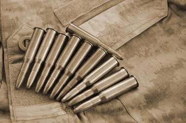 Rifle cartridges on a camouflage background. Top view. Sepia