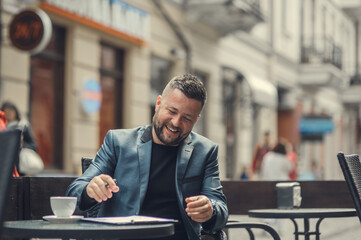 A smiling man sits in a cafe and writes a work plan on paper.Portrait of a stylish handsome young...