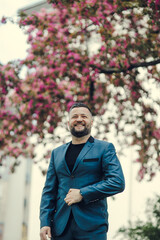 Fototapeta premium Portrait of a successful young guy.Portrait of handsome successful smiling man near flowering tree in park.