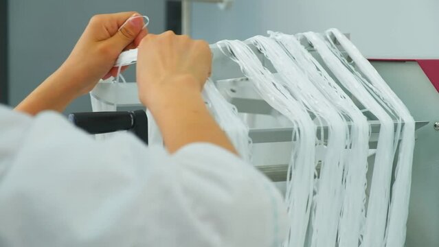 Closeup of polymer thread is removed from winding wheel, slow motion