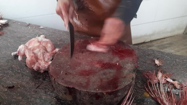 Men cutting raw chicken meat at the outdoor workshop in India. Butcher cutting pieces of chicken meat waiting for customers.