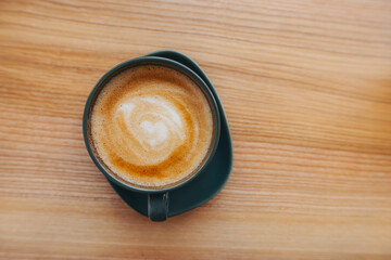 A cup of coffee stands on a wooden table in a cafe