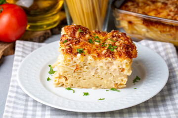 Pasta casserole bechamel sauce topped with melted mozzarella cheese and served in a white baking dish on a table (Turkish name; firinda makarna or firin makarna)