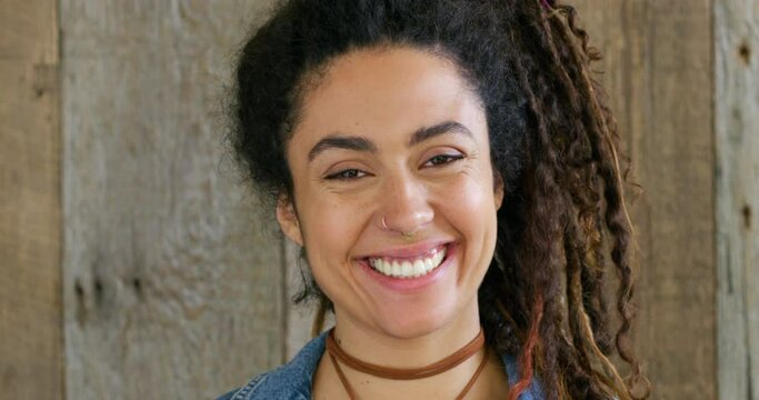 Closeup of a laughing, trendy and edgy woman or musician with dreadlocks hairstyle, smiling and happy expression. Headshot, face and portrait of funky, stylish and boho rocker against wood background
