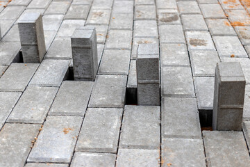 Pavement repairs and paving slabs laying on the prepared surface, with tile cubes in the background. Laying paving slabs in the pedestrian zone of the city. Paving slabs and curbs.