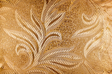 The surface of the fabric is silk, satin. Leaf pattern embroidered on golden fabric top view.