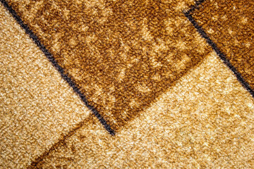 The surface texture of the carpet is brown and beige color. Woolen carpet pattern. Surface carpet.