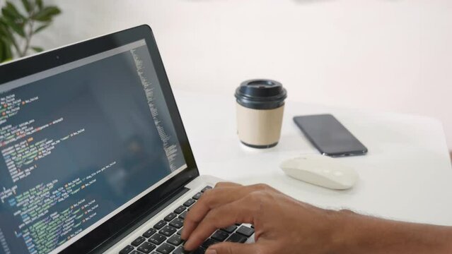 Web application development. programmer man writing program code sitting at workplace in office, software developer hands coding HTML programming with laptop computer, IT start up concept, back view