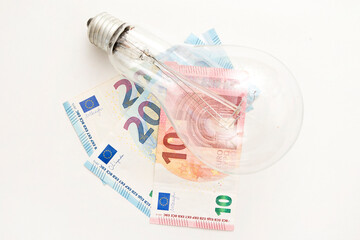 Light bulb on euro banknotes. Cost of electricity and expensive energy concepts. Increasing consumption, energy crisis. Inflation. Price level are getting more expensive annually.