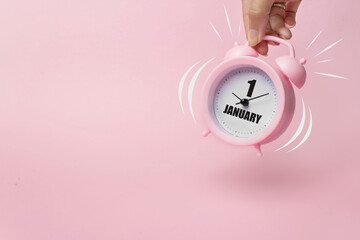 Obraz premium January 1st . Day 1 of month, Calendar date. The morning alarm clock jumping up from the bell with calendar date on a pink background. Winter month, day of the year concept.