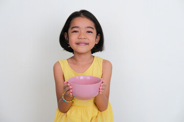 Asian kid smiling to the camera while holding empty dinner bowl