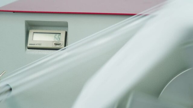 Extreme closeup of polymer thread on the winding wheel in process of winding. Small display on the back