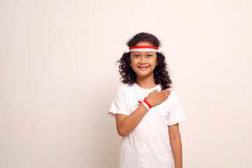 Adorable asian girl standing while showing respect hand gesture. Indonesian independence day concept