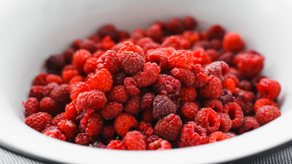 Harvested ripe red raspberries in white bowl. Close-up, selective focus