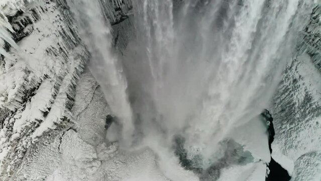 A beautiful large waterfall in Iceland in mid-winter covered by the snow around it and the clouds makes it even better.