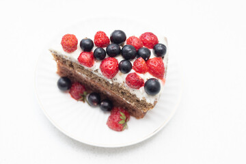 Homemade vanilla birthday cake decorated with berries: strawberries, blueberries, raspberries on plate
