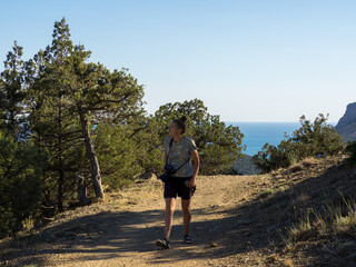 Woman with photo camera on blue sea background, relic juniper grove
