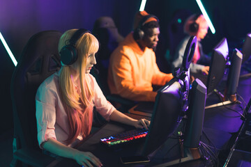 Fototapeta na wymiar Three teenagers wearing colorful clothes playing online game together wearing headsets using professional gaming setup. . High quality photo