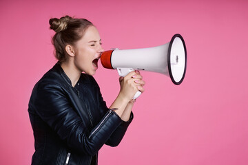 Caucasian female teenager holding megaphone and shouting in the studio