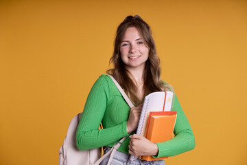 Portrait of smiling caucasian student girl holding school books and  wearing schoolbag