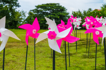 Pink pinwheel standing in garden,windmill in green meadow.