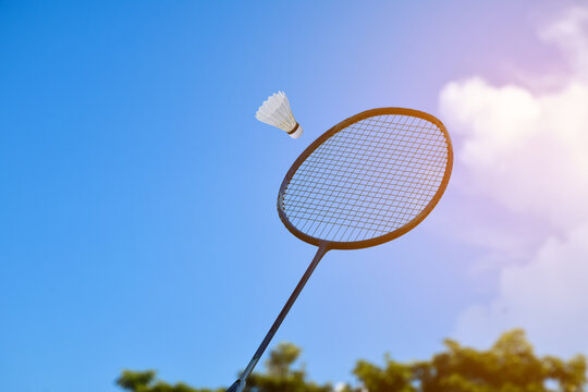 Badminton racket and badminton shuttlecock against cloudy and bluesky background, outdoor badminton playing concept. selective focus on racket.