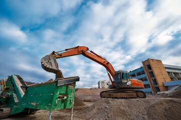 Excavator loads soil in mobile crushing and sorting complex