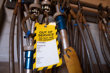 Safe workplaces practices yellow out of service warning tag sign placing on damaged faulty unsafe...