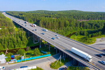 Active traffic of cars on a wide highway and a bridge. Flight over the automobile bridge across the river Lattice. Yekaterinburg. Russia