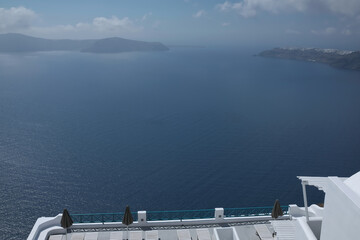 A beautiful whitewashed  terrace with sun beds and a breathtaking view over the Aegean Sea in Santorini Greece