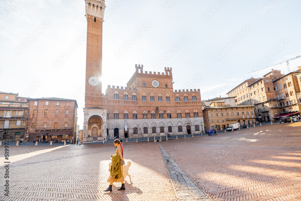 Wall mural morning view on the main square of siena city with town hall and woman walks with a dog. concept of 