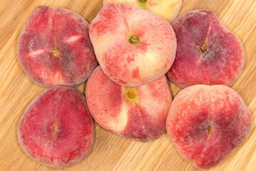 Top view of the flat peaches on a wooden surface