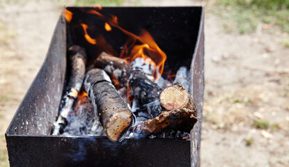 Burning red hot sparks fly from fire. Barbecue gril with glowing and flaming hot charcoal and firewood