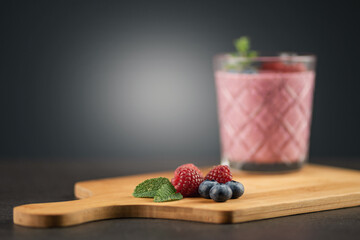 Smoothie Himbeere, Blaubeere, Minze auf Holzbrett