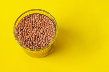 a glass with lentils on a yellow background