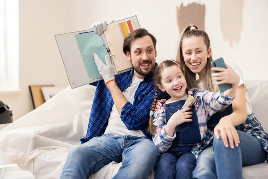 Man woman and beautiful daughter went online with their relatives to show them color they wanted to paint the walls in living room. The family is very pleased that they have started renovations.