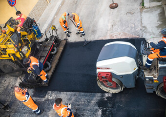 Worker on Asphalting paver machine during Road street repairing works