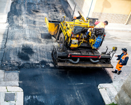 Worker on Asphalting paver machine during Road street repairing works