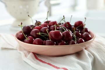 Fresh ripe cherries and towel on white table, closeup