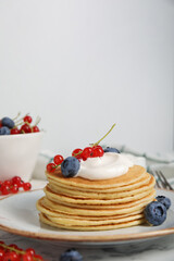 Tasty pancakes with natural yogurt, blueberries and red currants on marble table