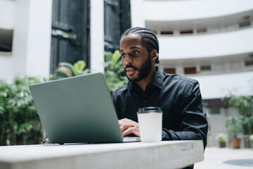Fototapeta premium Young businessman working on his laptop in a hall of a condo
