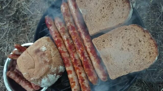Top view footage of delicious sausages an toast on hot barbecue.