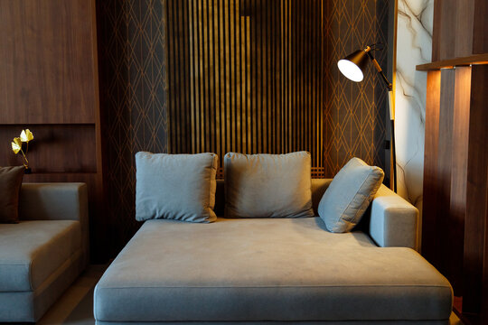 Modern interior design of living room with huge sofa, wooden planks on wall, golden ornate wallpaper