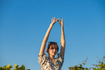 beautiful girl against the sky.  arms raised lightly above the head against the sky.  feminine...